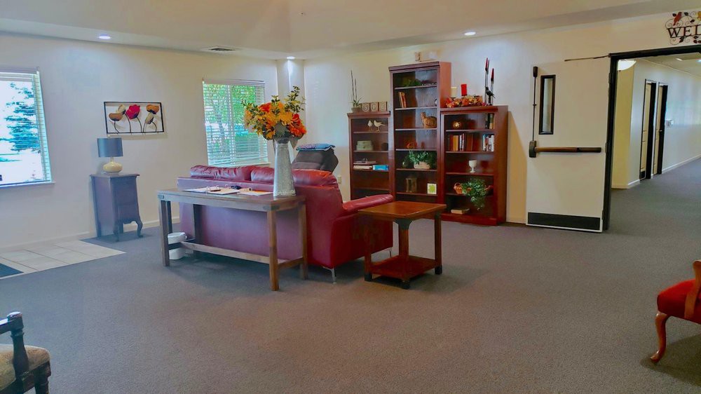 A cozy living room with a red sofa, bookshelf, and a table adorned with flowers.