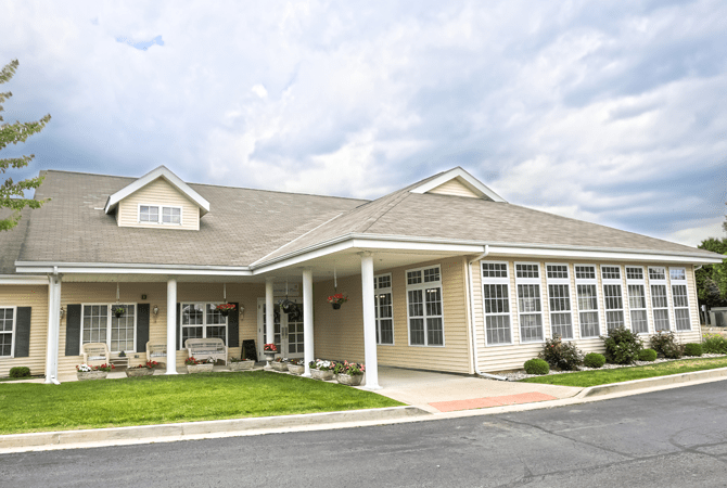 A charming residential building with a covered porch and well-maintained lawn under a cloudy sky.