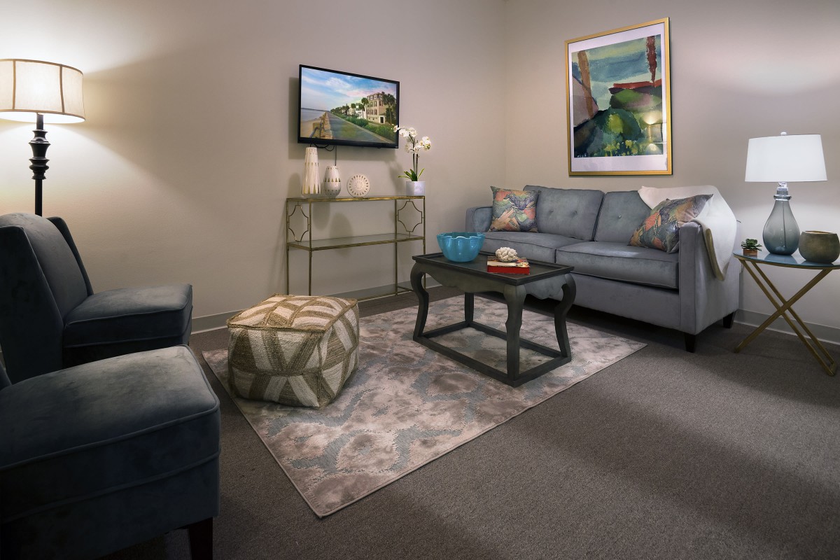 A cozy living room with a sofa, coffee table, rug, and wall-mounted television.