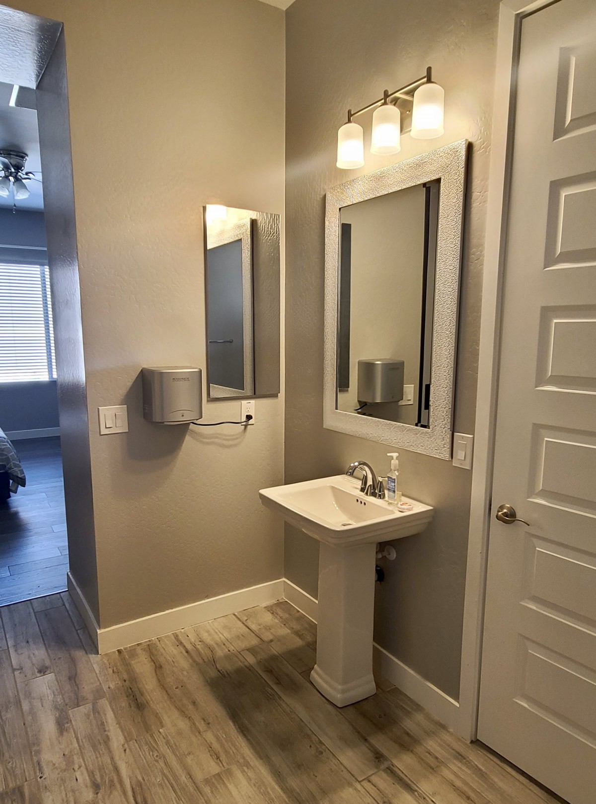 A modern, minimalist bathroom with a pedestal sink and large mirrors.
