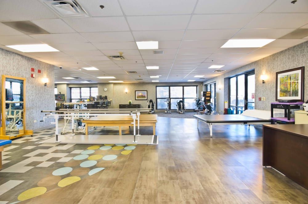 A spacious rehabilitation center with various exercise equipment and therapy areas.