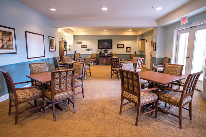 A cozy dining area with multiple tables and chairs, adorned with framed pictures and a television on the wall.