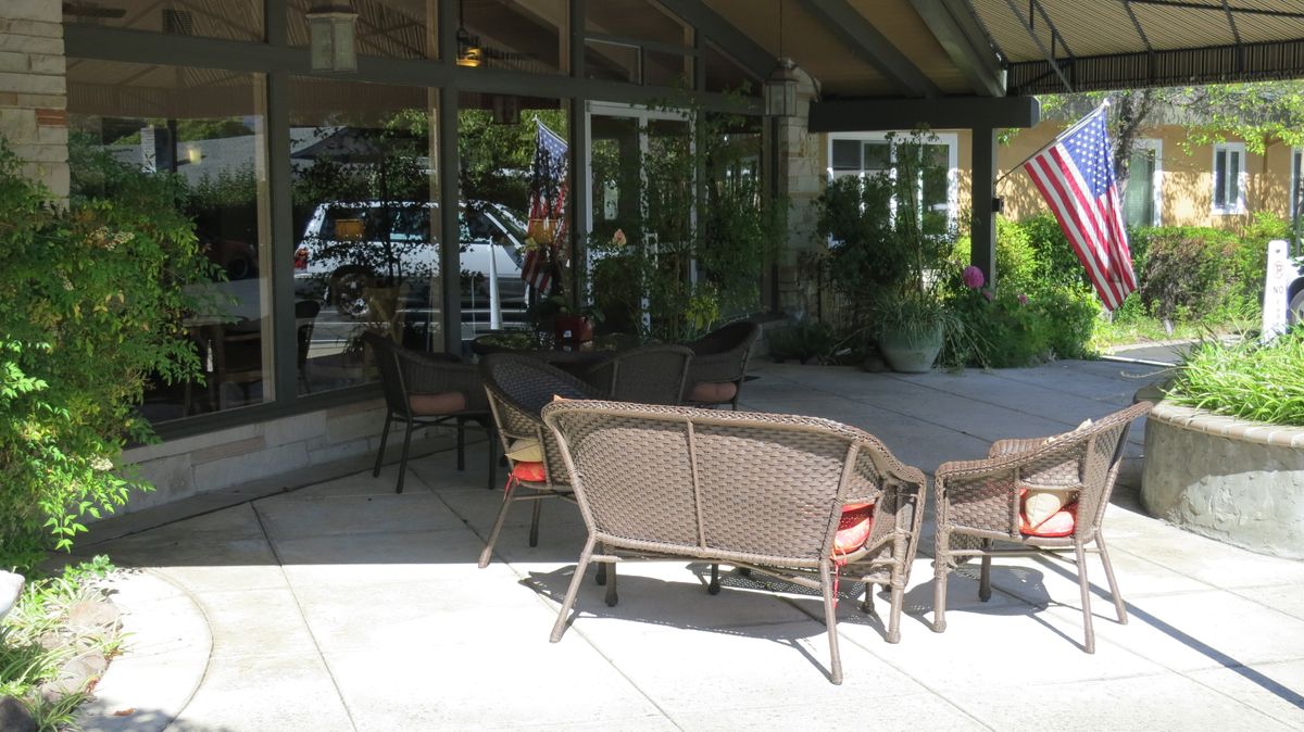 An outdoor patio area with wicker seating and glass windows reflecting the surroundings.