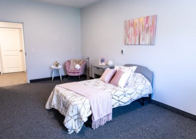 A cozy bedroom with a bed, decorative pillows, and pastel accents.