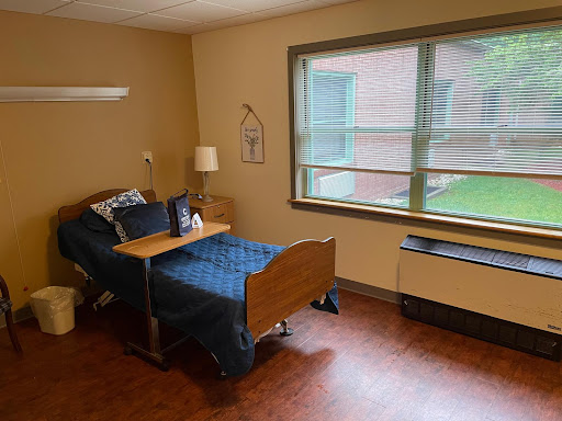 A cozy room with a single bed, lamp, and window view.