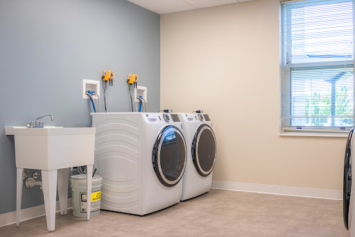 A clean and modern laundry room featuring a washing machine, dryer, and utility sink.