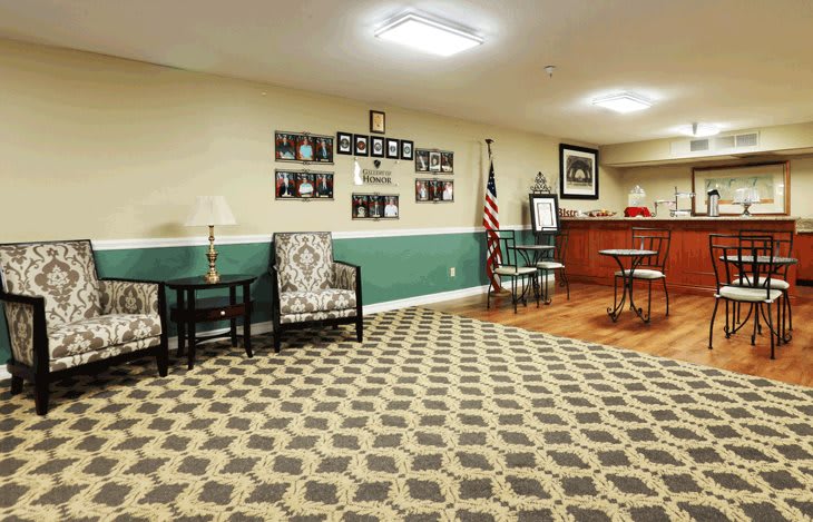 A cozy waiting room with patterned carpet, comfortable seating, and a reception area.