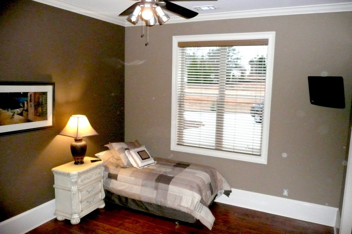 A cozy bedroom with a single bed, nightstand, and window.