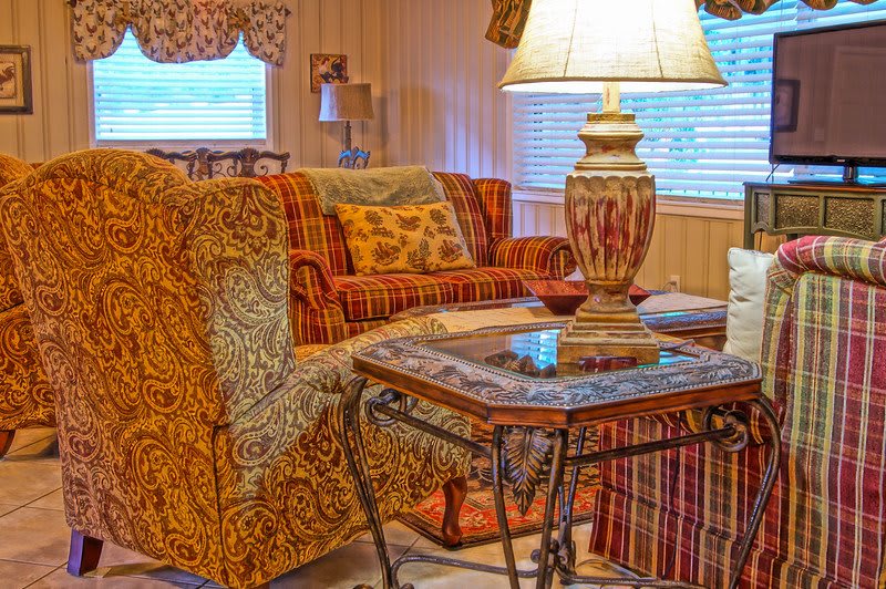 A cozy living room with patterned furniture, a decorative lamp, and a glass table.