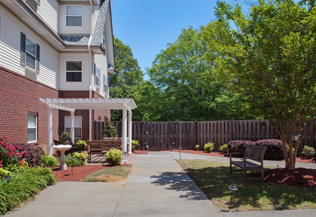 A well-maintained backyard with a pergola, patio, and outdoor seating surrounded by trees.