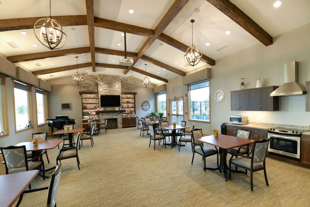 A welcoming community room featuring wooden beams, chandeliers, and ample seating.
