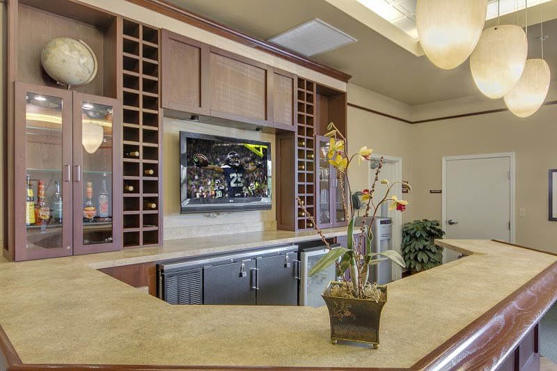 A bar interior with a counter, cabinets, a television, and decorative flowers.