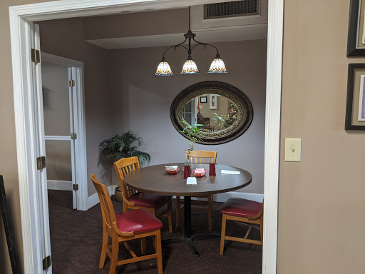 A cozy dining area featuring a round table, four chairs, pendant lighting, and a decorative mirror.