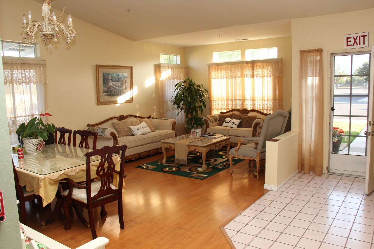 A cozy living room with an adjoining dining area, featuring classic furniture and warm lighting.