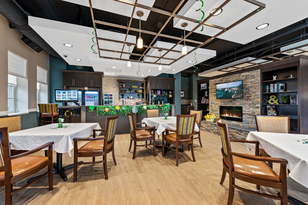 A modern restaurant interior with neatly arranged tables and chairs, featuring a cozy fireplace and a bar area.