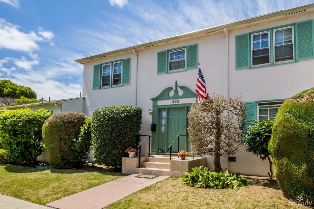 A two-story residential house with a garden and an American flag.