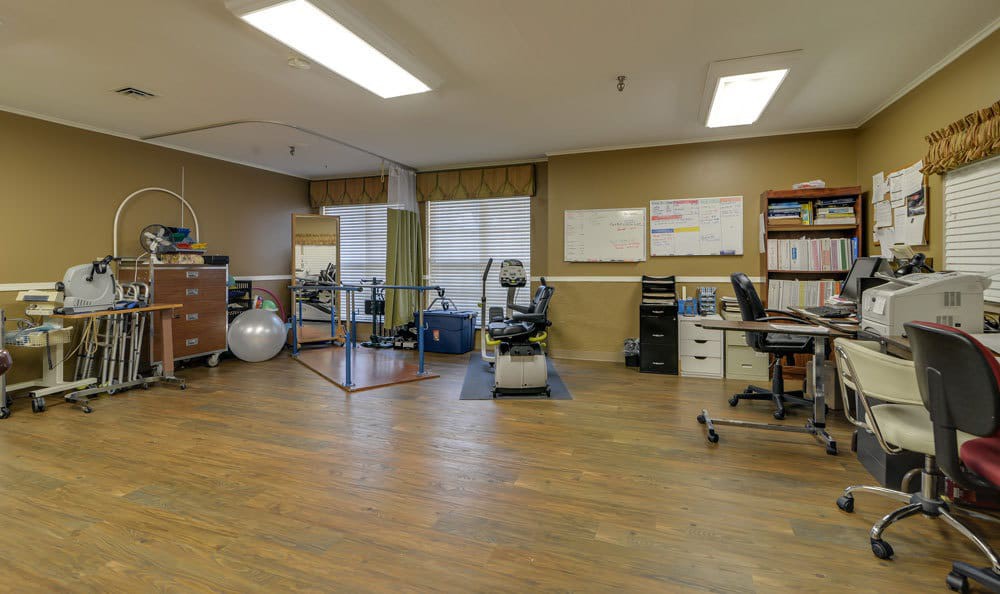 A spacious rehab gym with various exercise equipment and therapy tools.