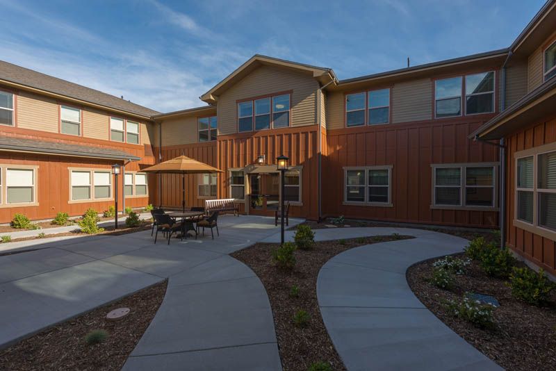 A modern residential building with a courtyard featuring pathways and outdoor seating.