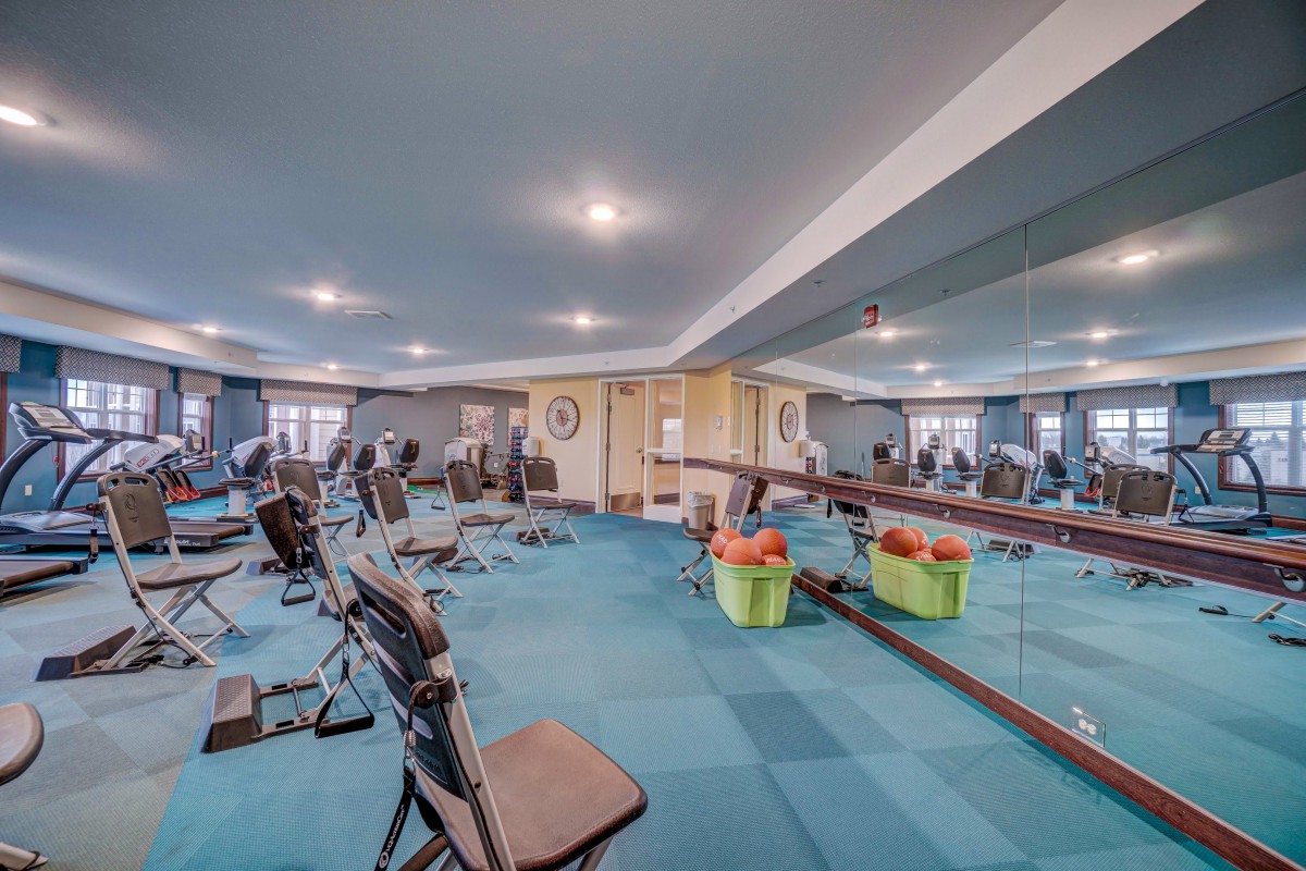 A spacious gym with various exercise equipment and large mirrors.