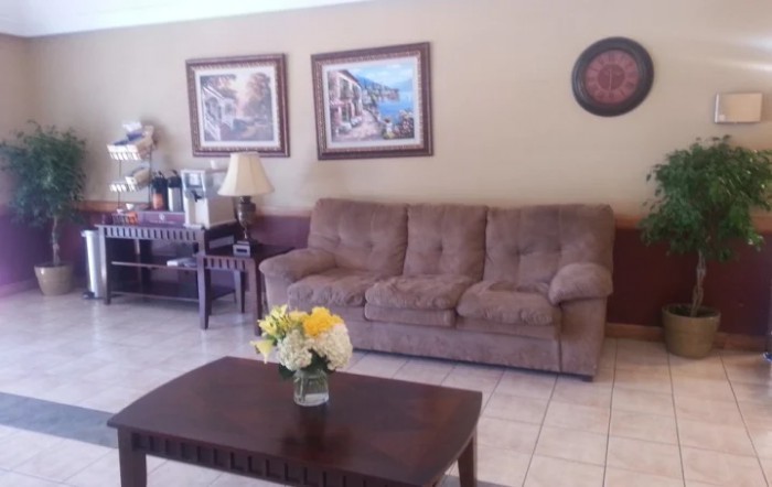 A cozy living room with a brown sofa, a coffee table featuring flowers, and decorative artwork on the walls.