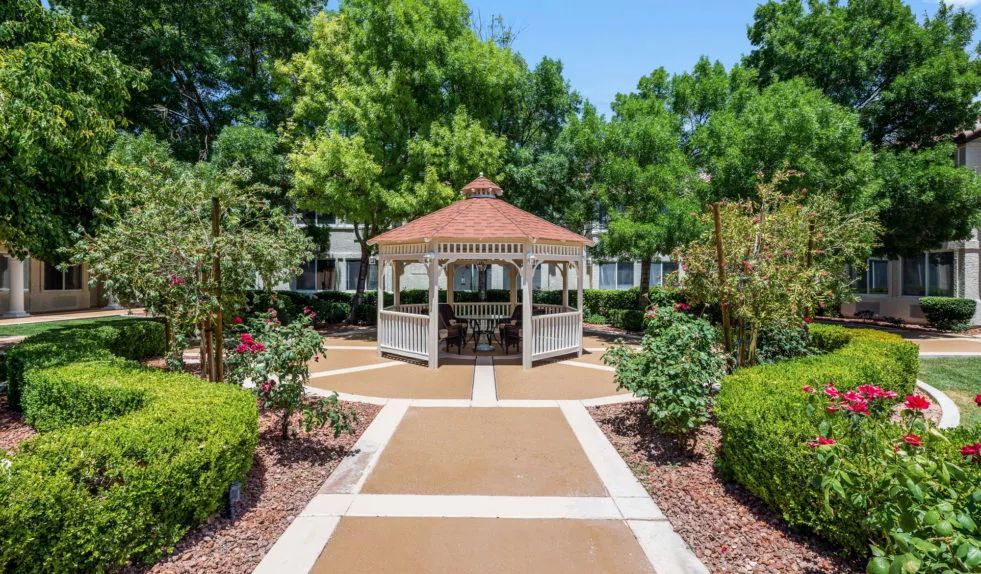 A charming gazebo in a beautifully landscaped garden with pathways and lush greenery.