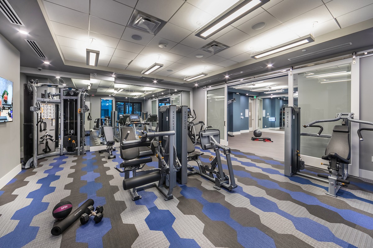 A modern gym with various exercise equipment and spacious workout areas.