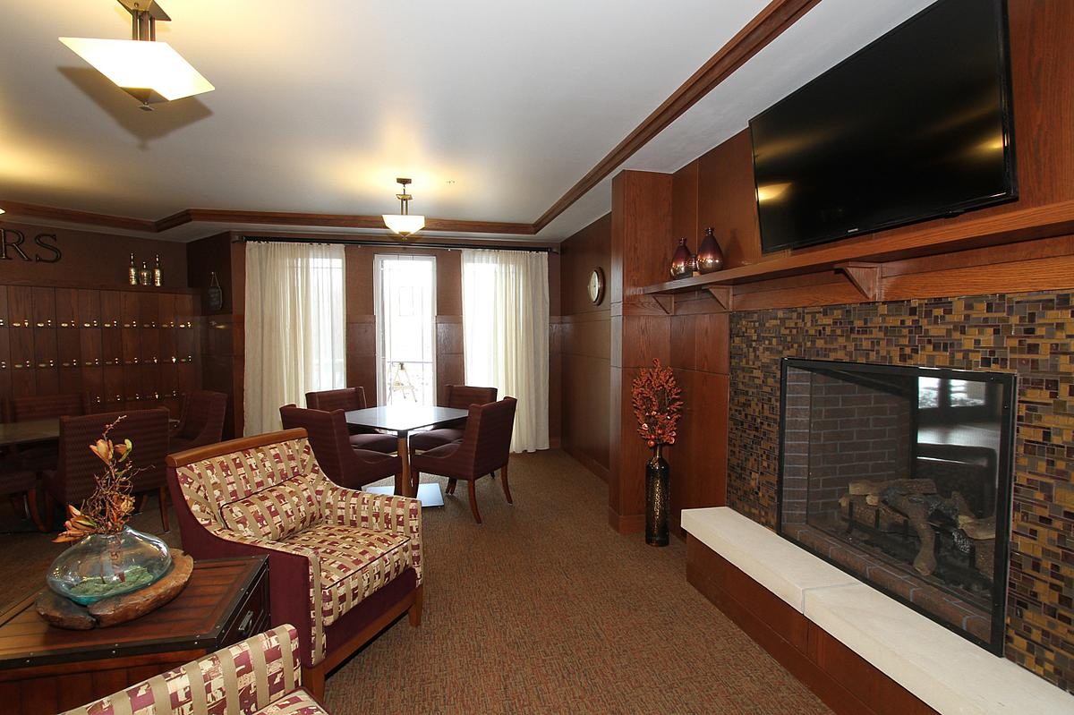 A cozy living room with a fireplace, comfortable seating, and a mounted television.