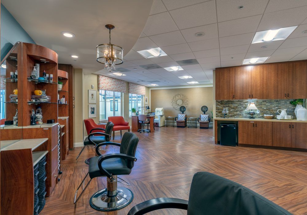 A spacious and well-lit hair salon with stylish chairs and wooden flooring.