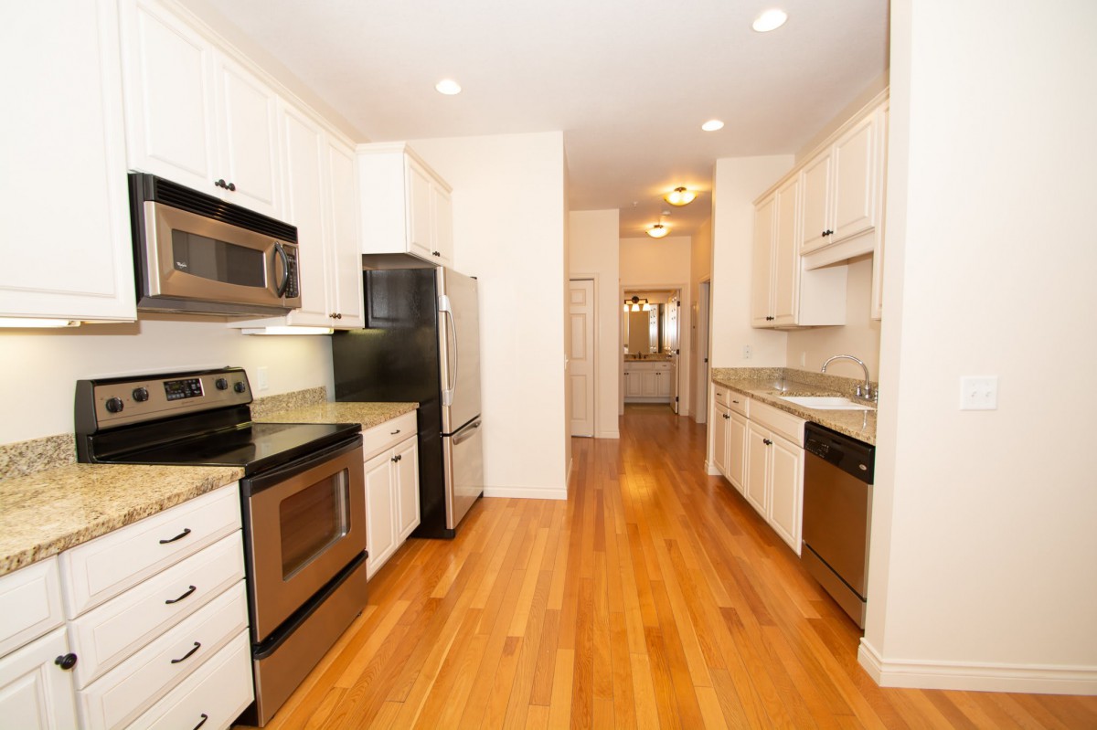 A modern kitchen with stainless steel appliances and wooden flooring.