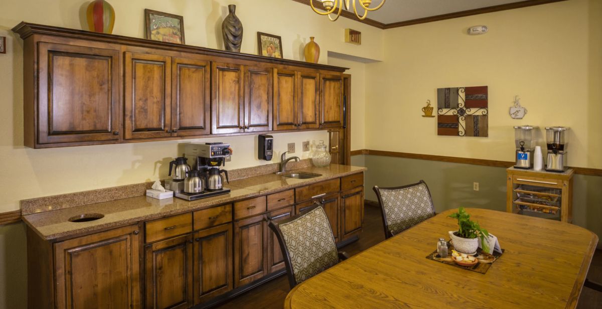 A cozy kitchen and dining area featuring wooden cabinets, a coffee maker, and a dining table with chairs.