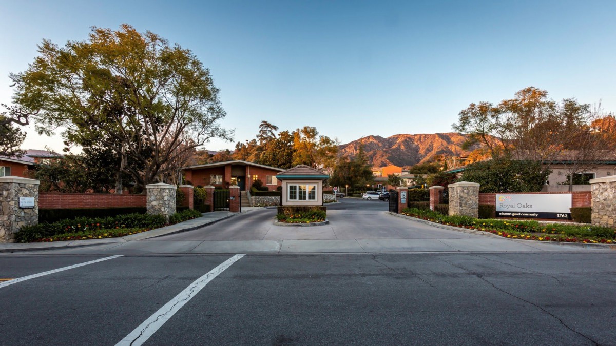 Entrance to a gated community with mountains in the background at sunset.