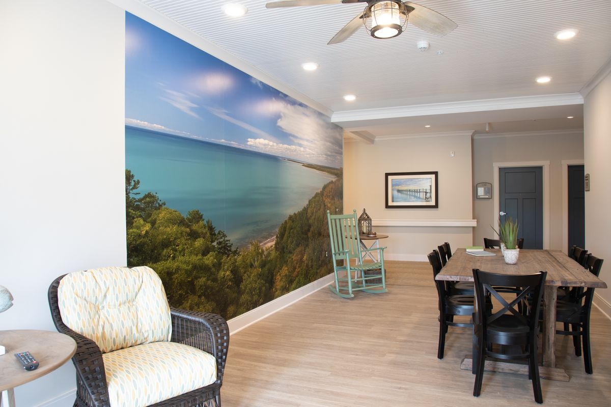 A modern living and dining space featuring a large coastal-themed wall mural.