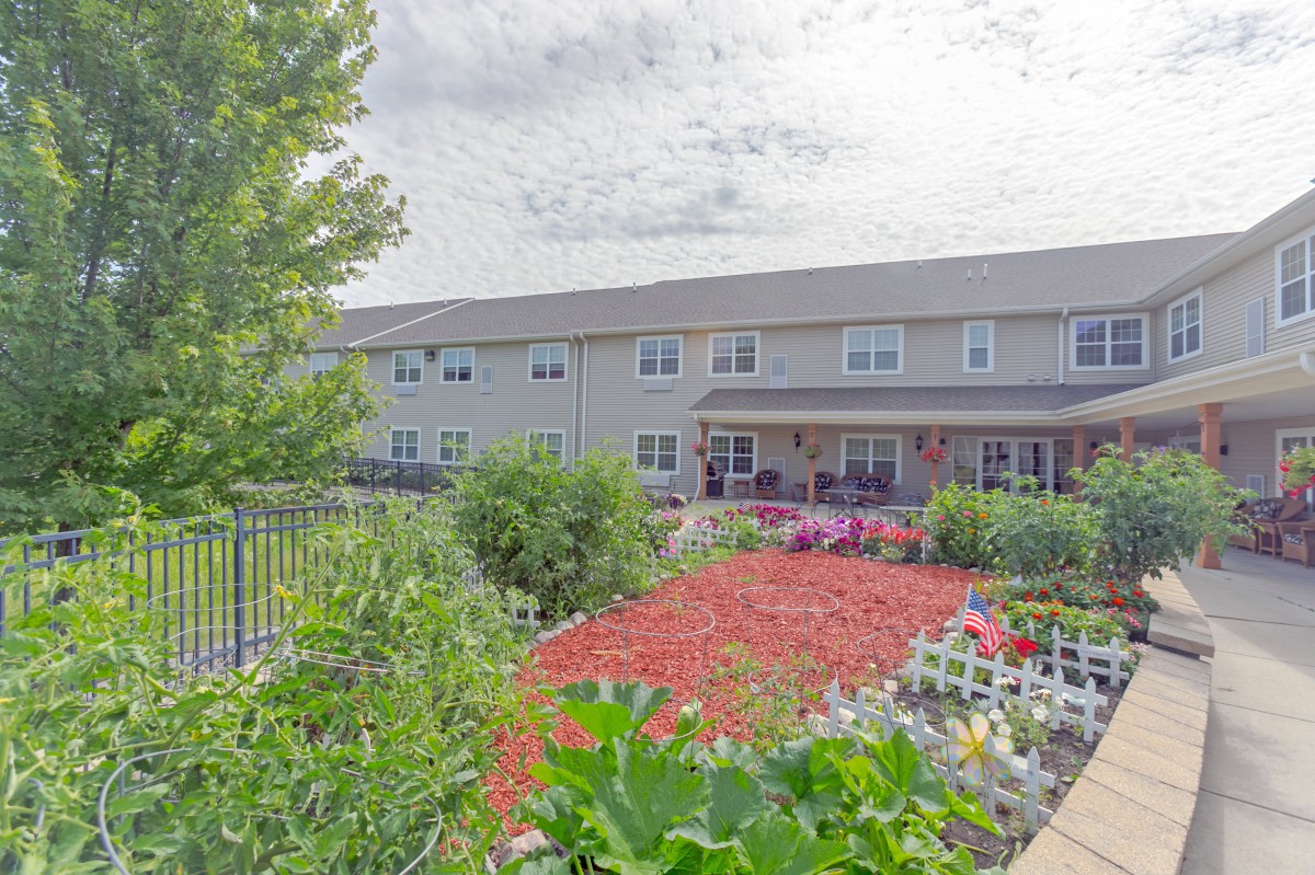 A well-maintained garden in front of a residential building with colorful flowers and greenery.
