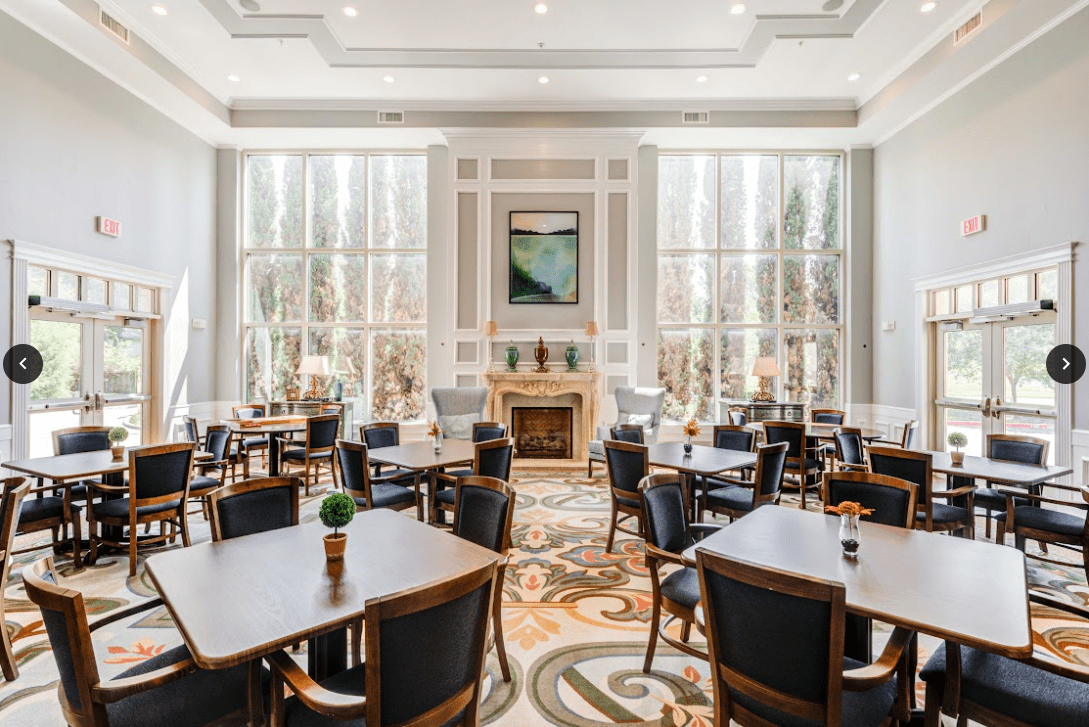 A spacious dining room with elegant decor, featuring large windows that allow natural light to fill the space.