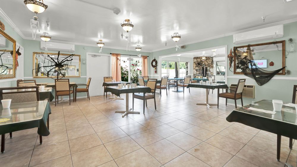 A spacious dining area with multiple tables and chairs, featuring neutral tones and bright lighting.