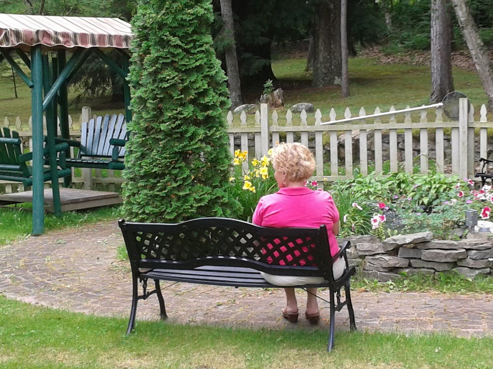 A person sits on a bench in a garden, enjoying the peaceful surroundings.