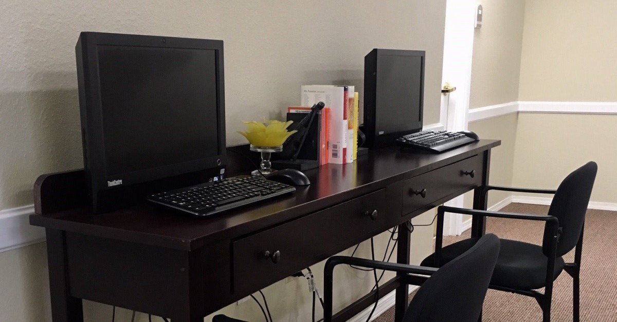 A tidy office workspace featuring two computers on a wooden desk.