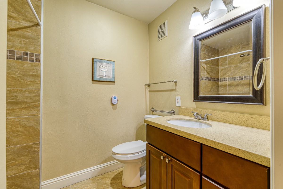 A modern bathroom featuring a sink with a wooden cabinet, a mirror, and simple wall decor.