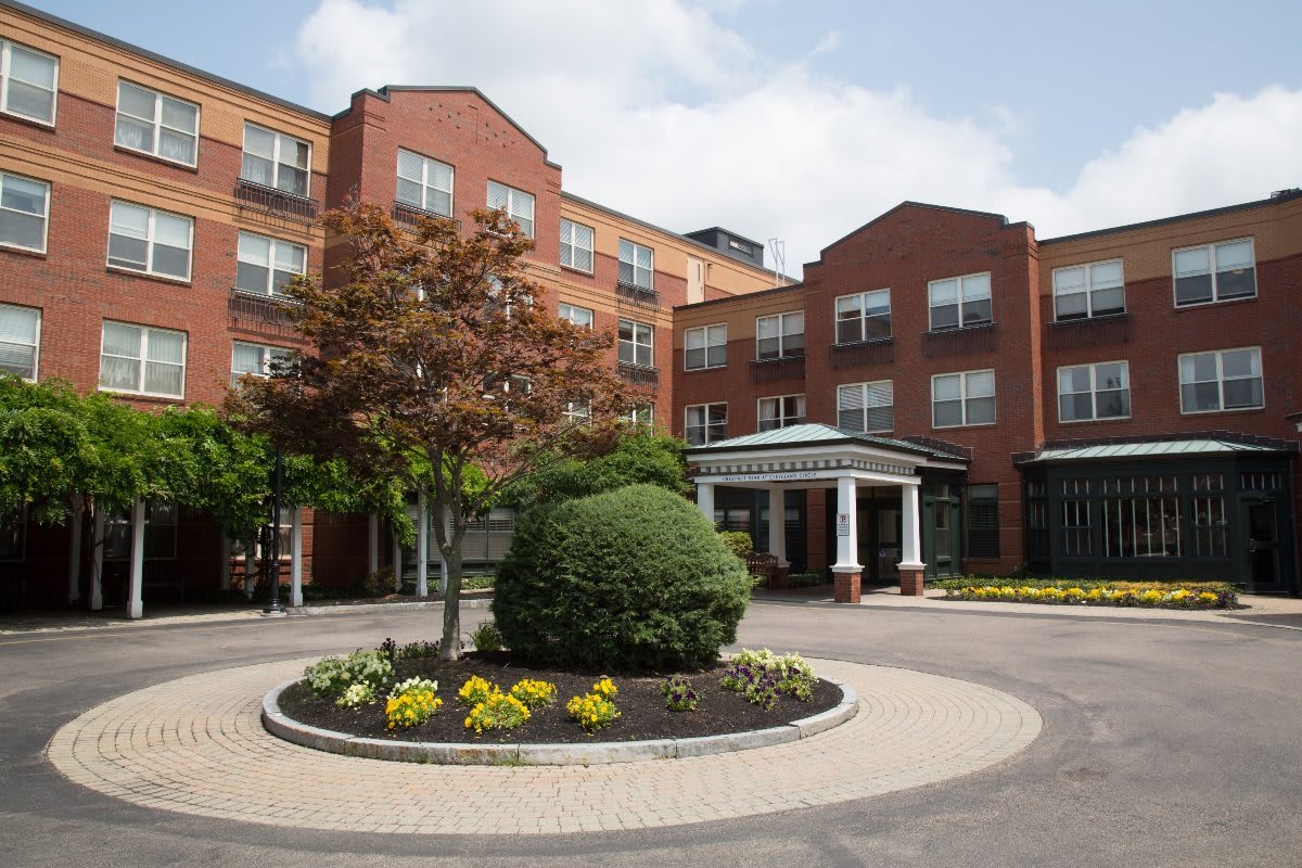 A well-maintained hotel entrance with a circular driveway and landscaped gardens.