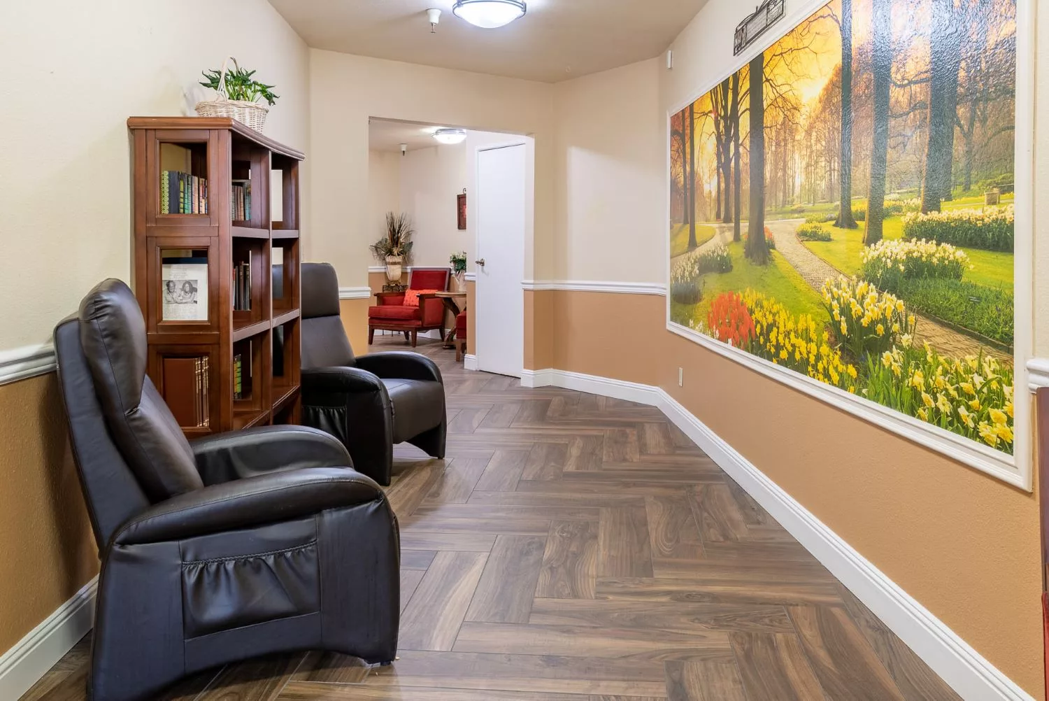 A cozy living space with armchairs, a bookshelf, and vibrant wall art.