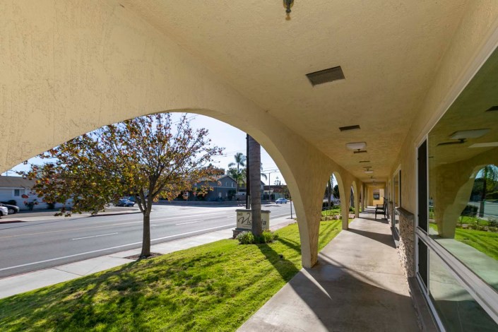 A sunny street view with arched sidewalks and trees.