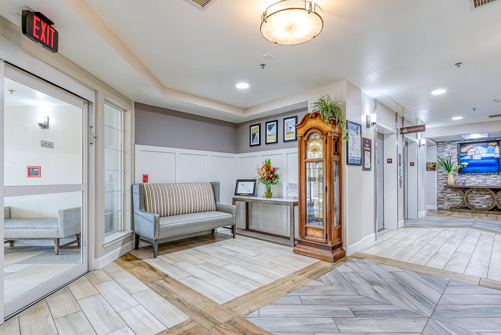 A well-decorated hallway with a sofa, grandfather clock, and framed pictures on the wall.
