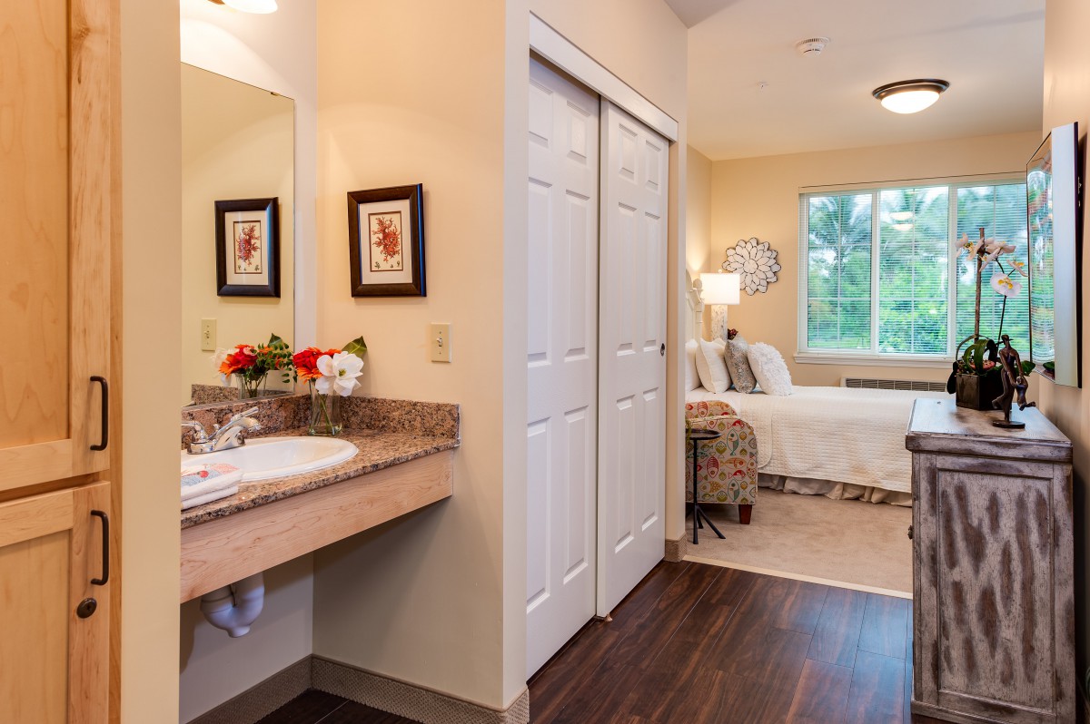 A cozy bedroom with an adjoining bathroom, featuring warm decor and ample natural light.