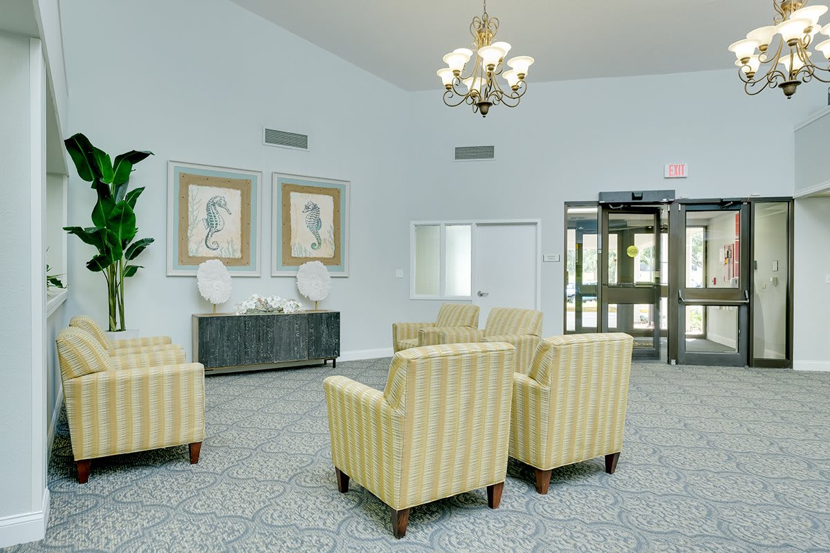 A well-lit lobby with striped chairs, a chandelier, and decorative artwork on the walls.