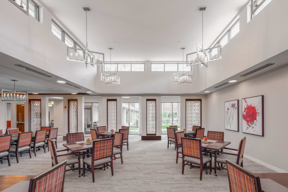 A spacious and modern dining area with neatly arranged tables and chairs, featuring contemporary lighting fixtures.
