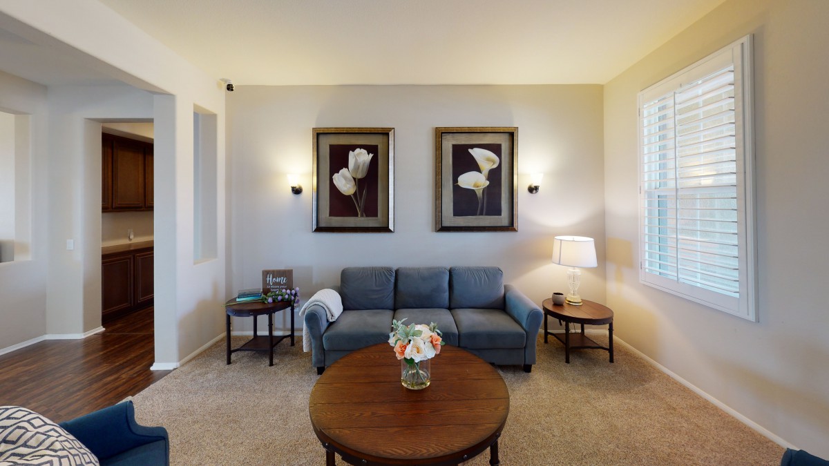 A cozy living room with a blue sofa, decorated with elegant wall art and a wooden coffee table.
