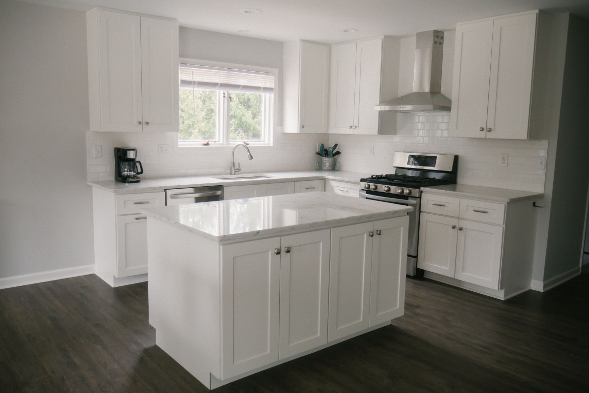 A modern kitchen with white cabinets, a central island, and stainless steel appliances.