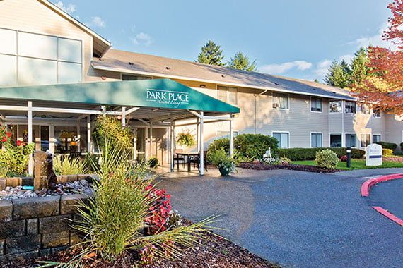 A hotel entrance with a green awning and landscaped surroundings.
