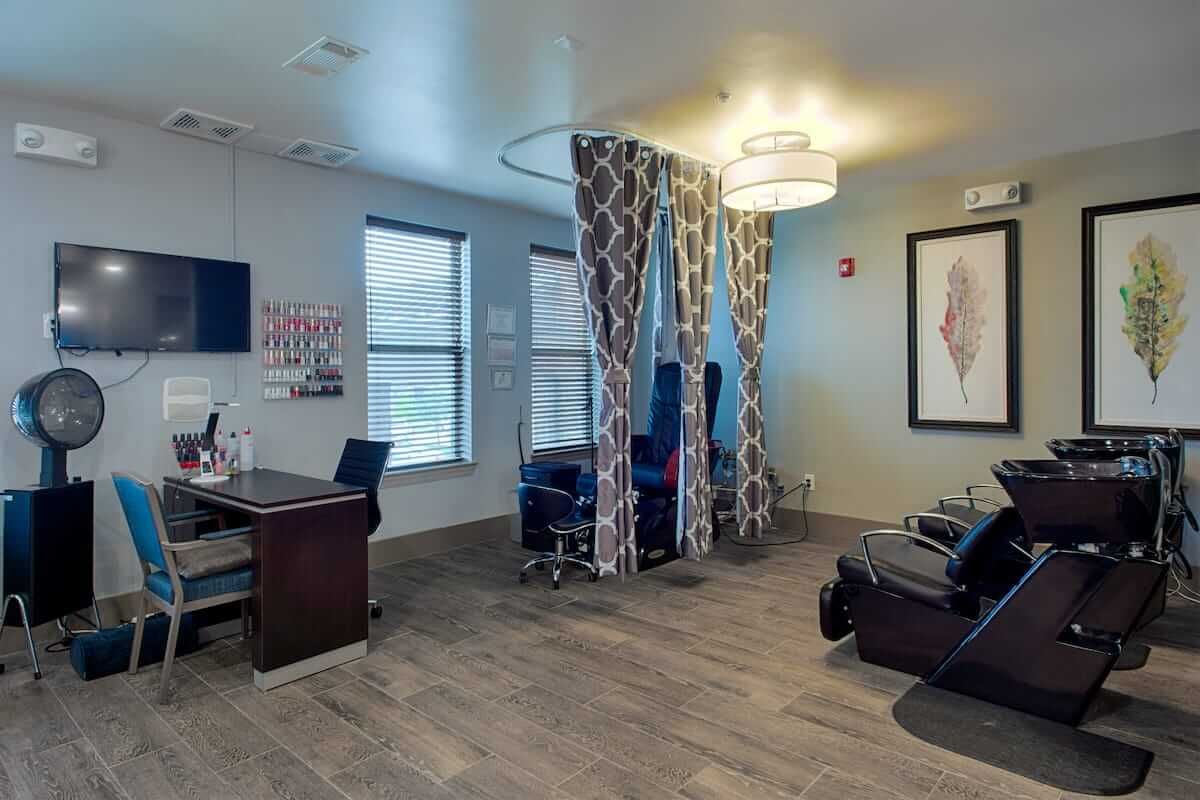 A modern salon interior with seating, a desk, and stylish curtains.
