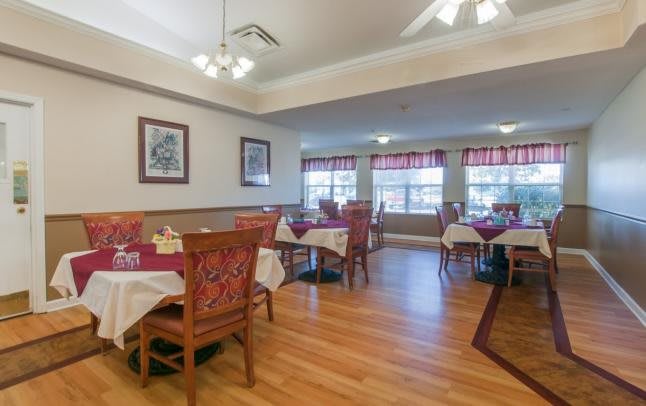 A cozy dining room with neatly arranged tables and chairs on a wooden floor.